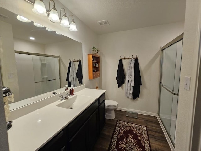 full bath with wood finished floors, vanity, visible vents, baseboards, and a stall shower