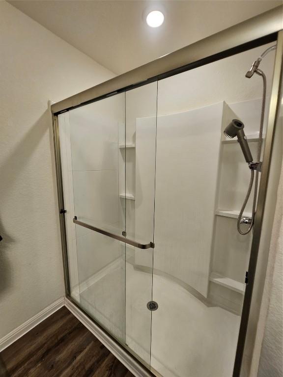 bathroom featuring a stall shower, wood finished floors, and baseboards