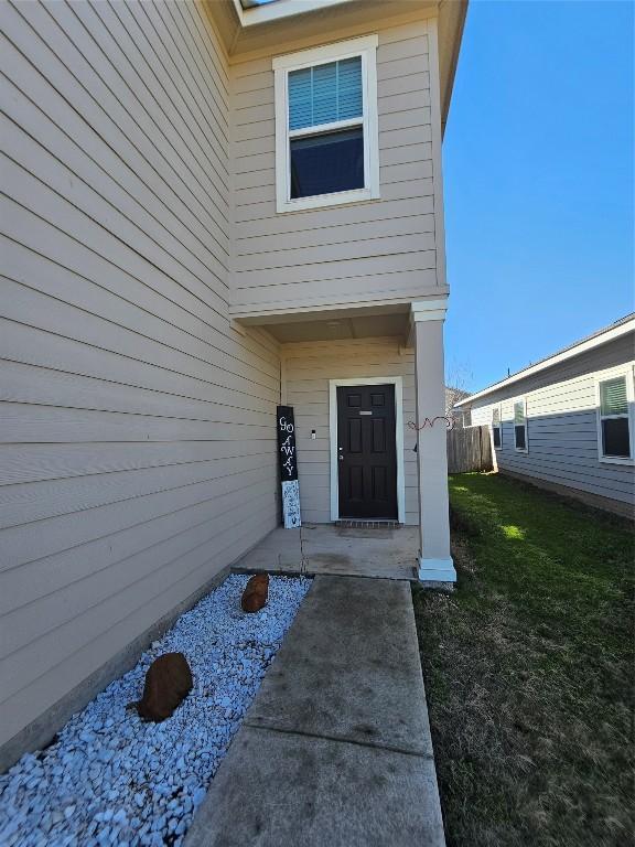 entrance to property featuring fence and a lawn