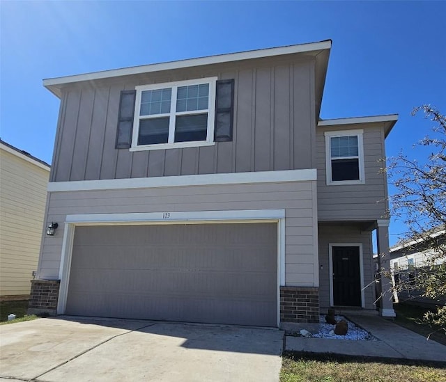 view of front of house with driveway, an attached garage, board and batten siding, and brick siding