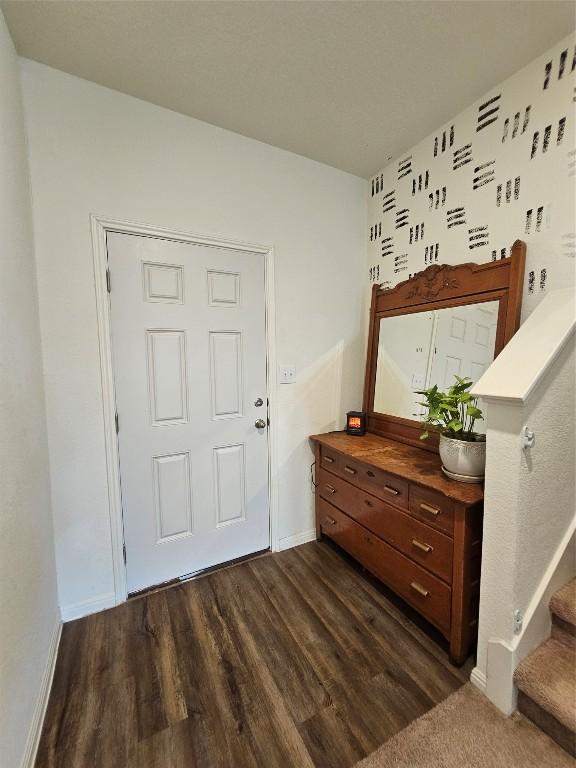 foyer with dark wood-type flooring, stairway, and baseboards