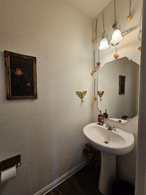 bathroom featuring a textured wall, baseboards, and wood finished floors