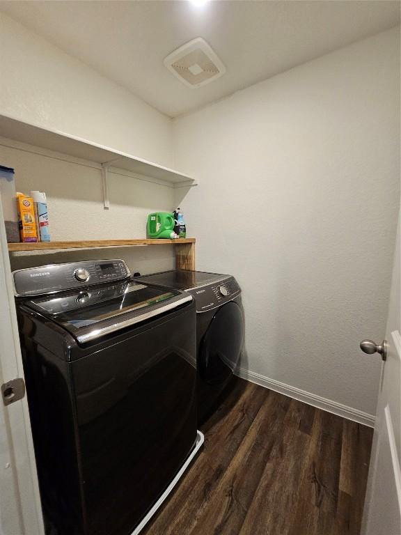 washroom with laundry area, baseboards, visible vents, dark wood finished floors, and washer and dryer