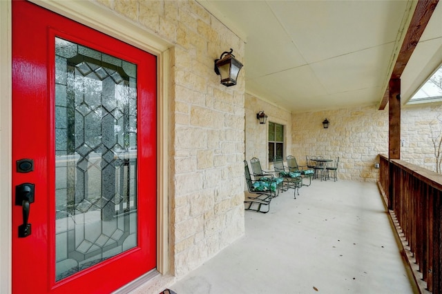 view of exterior entry with a porch and stone siding