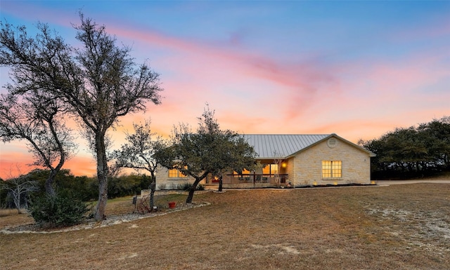 view of front of home with stone siding, metal roof, a standing seam roof, and a lawn