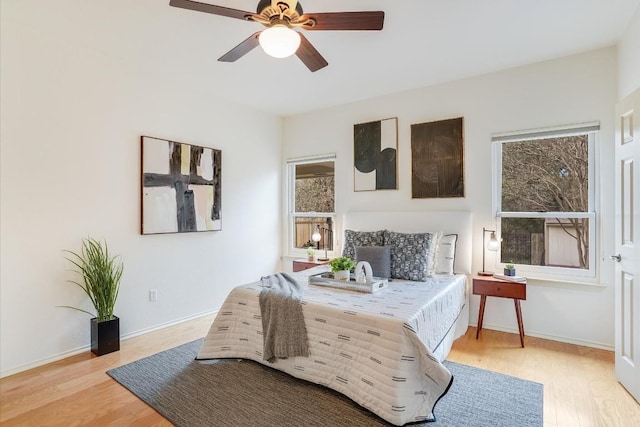 bedroom with ceiling fan, light wood finished floors, and baseboards