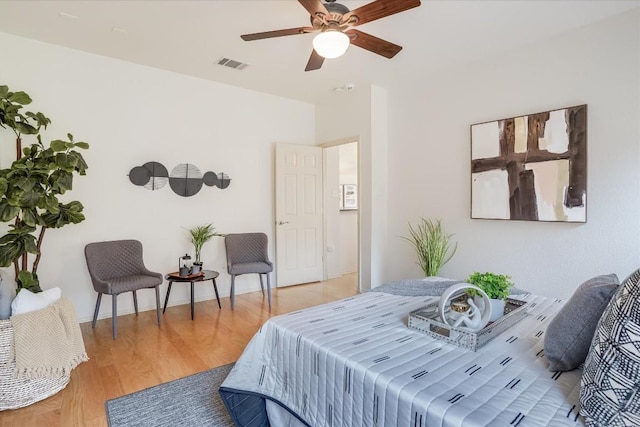 bedroom with baseboards, a ceiling fan, visible vents, and light wood-style floors