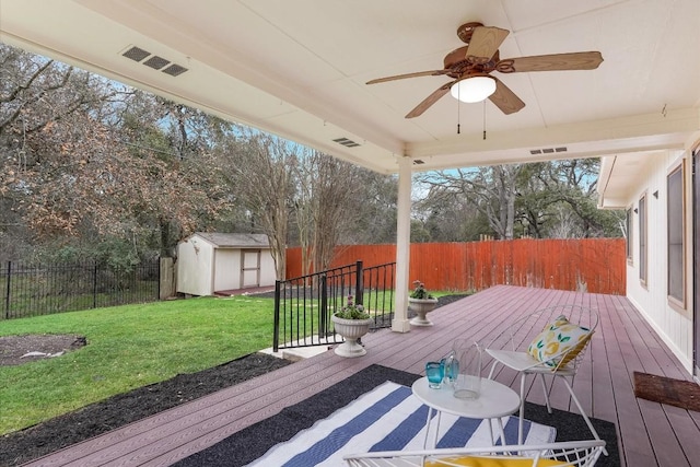 wooden terrace featuring an outbuilding, a yard, visible vents, a storage shed, and a fenced backyard