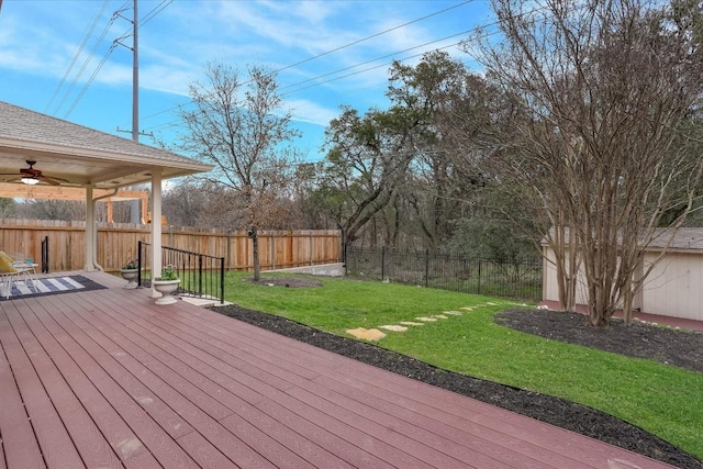 wooden deck featuring a fenced backyard, a ceiling fan, and a lawn