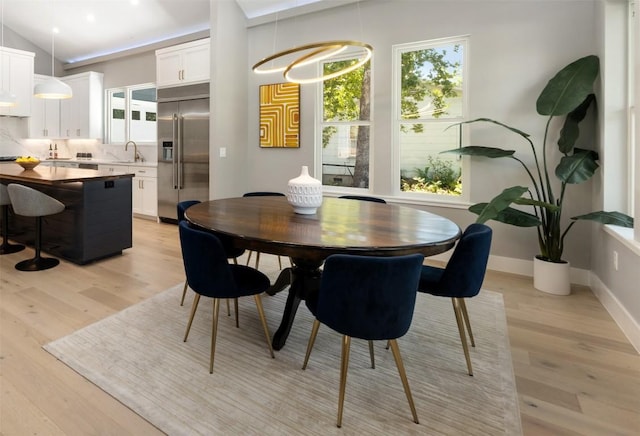 dining area with vaulted ceiling, light wood-style flooring, and baseboards