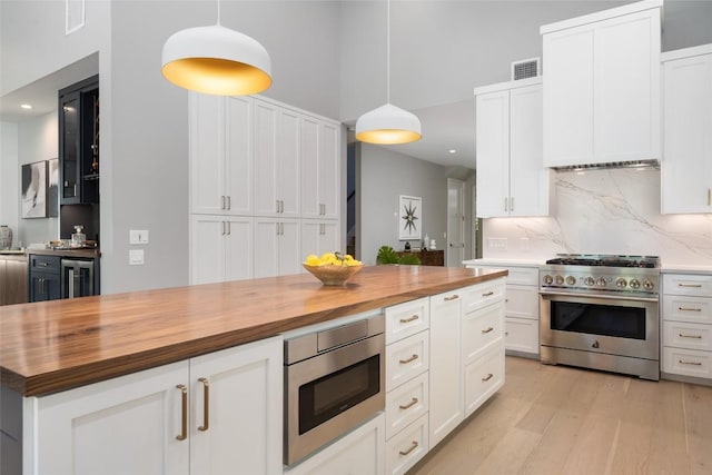 kitchen featuring hanging light fixtures, wood counters, white cabinets, and stainless steel appliances