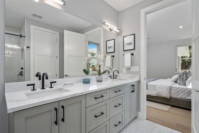 ensuite bathroom featuring connected bathroom, visible vents, a tile shower, and a sink