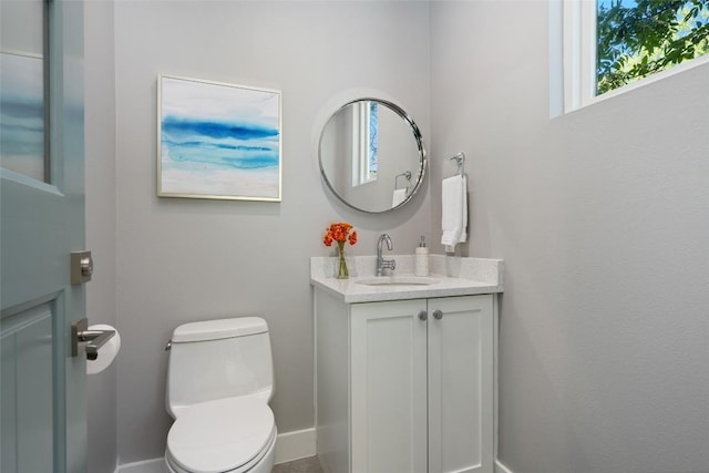 half bathroom with toilet, baseboards, and vanity