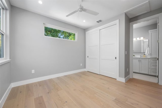 unfurnished bedroom with light wood-style flooring, visible vents, baseboards, a closet, and ensuite bath