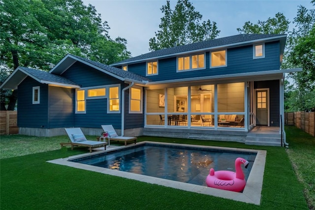 back of property featuring fence private yard, a shingled roof, a lawn, and a fenced in pool