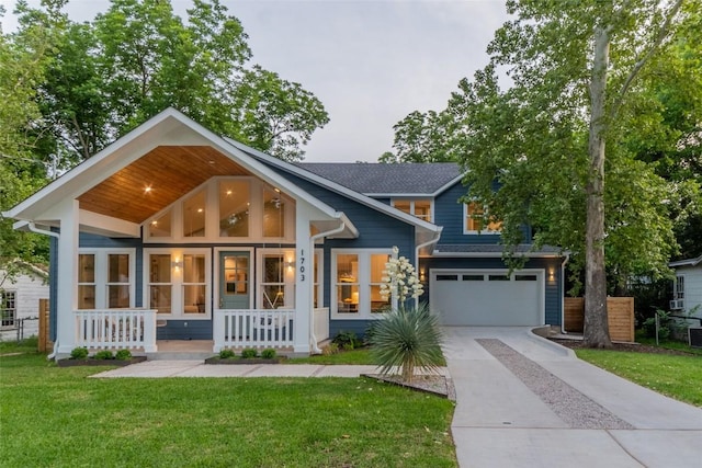 craftsman house with driveway, a garage, a porch, and a front yard