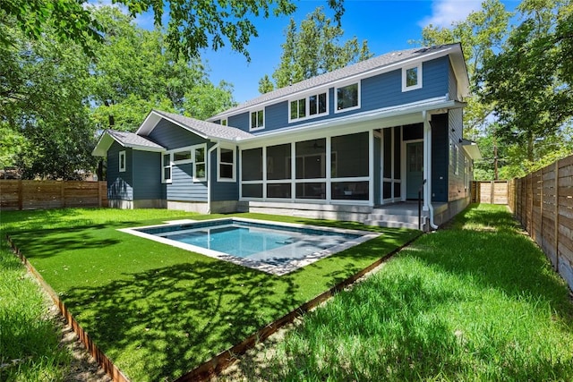 back of house with a lawn, a fenced backyard, a sunroom, and a fenced in pool