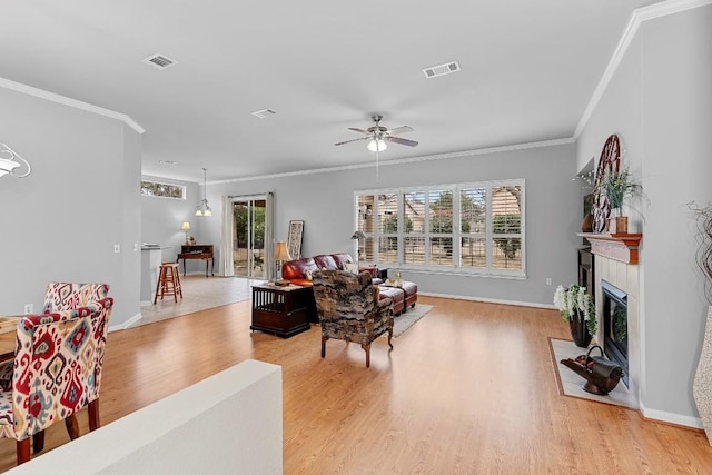 living room with a fireplace with flush hearth, visible vents, ornamental molding, and light wood-style flooring