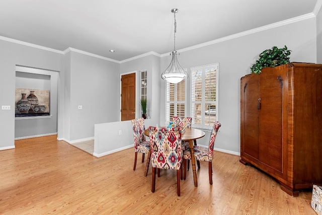 dining room featuring baseboards, ornamental molding, and light wood-style floors