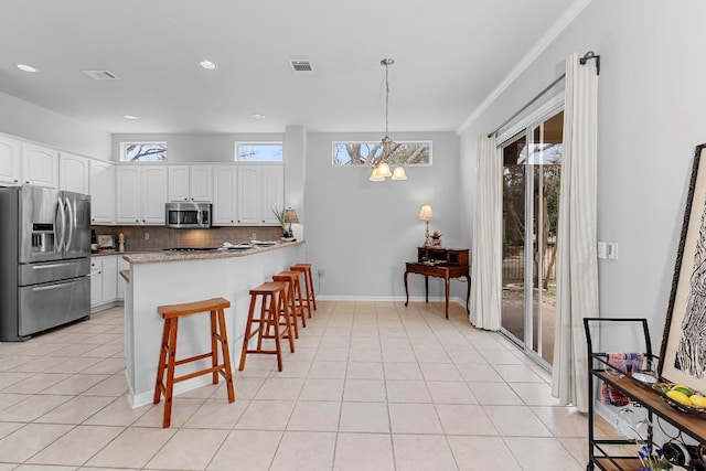 kitchen with a peninsula, visible vents, white cabinets, appliances with stainless steel finishes, and pendant lighting