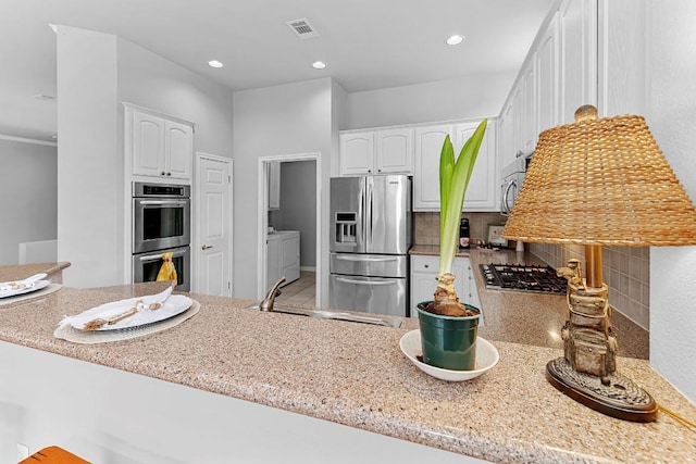 kitchen featuring stainless steel appliances, a sink, visible vents, white cabinetry, and backsplash