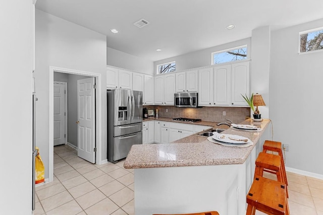 kitchen featuring stainless steel appliances, white cabinets, a sink, and a peninsula