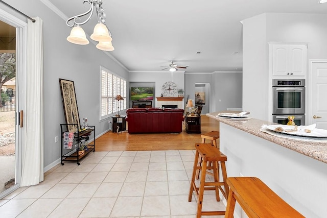 kitchen featuring double oven, white cabinets, open floor plan, light countertops, and hanging light fixtures