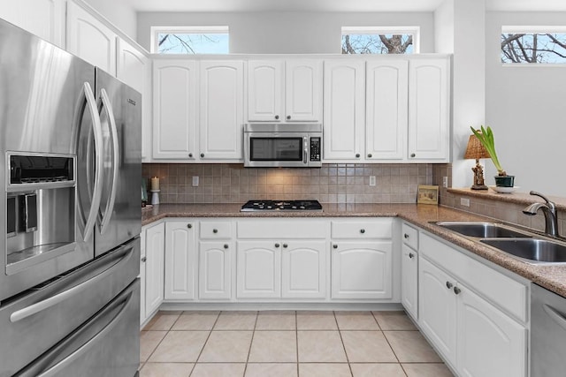 kitchen with stainless steel appliances, white cabinetry, a sink, and tasteful backsplash