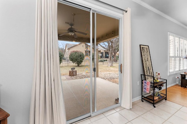 doorway with light tile patterned floors, crown molding, baseboards, and a ceiling fan