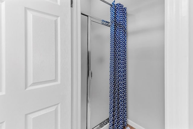 bathroom featuring a stall shower and baseboards