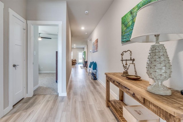 hallway featuring light wood-style flooring, baseboards, and recessed lighting