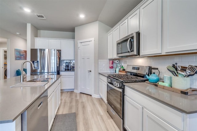 kitchen with appliances with stainless steel finishes, white cabinetry, a sink, and visible vents