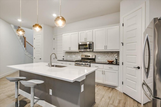 kitchen featuring stainless steel appliances, hanging light fixtures, a sink, and white cabinets