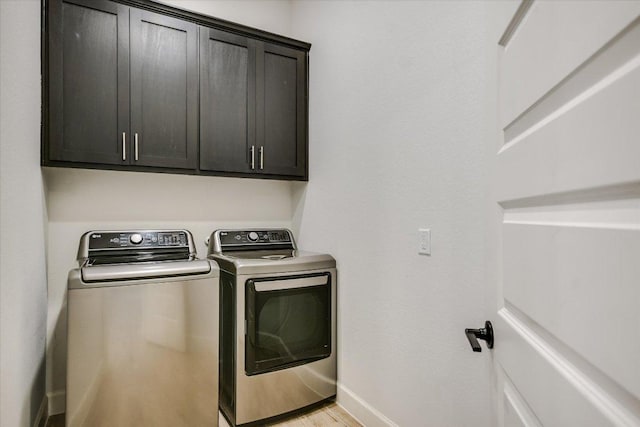 laundry area with light wood-type flooring, cabinet space, baseboards, and washer and clothes dryer