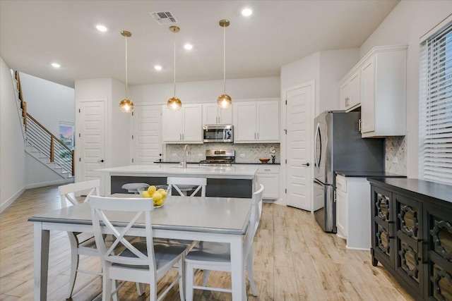 kitchen featuring decorative light fixtures, light wood finished floors, visible vents, appliances with stainless steel finishes, and white cabinetry