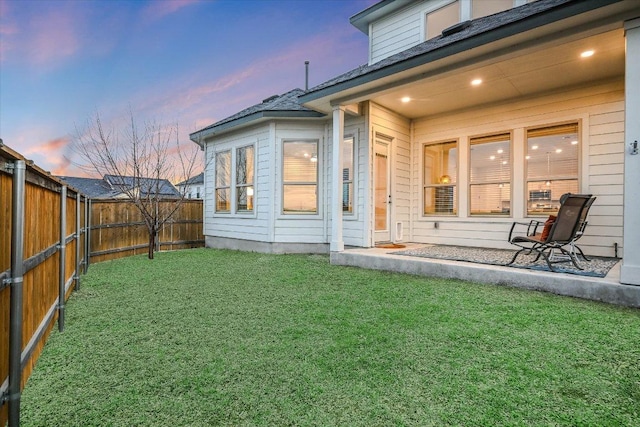 back of house featuring a fenced backyard and a lawn