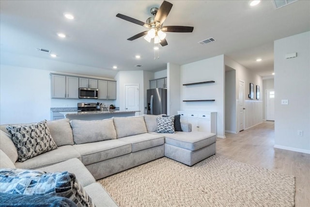 living room featuring light wood-style floors, a ceiling fan, recessed lighting, and baseboards