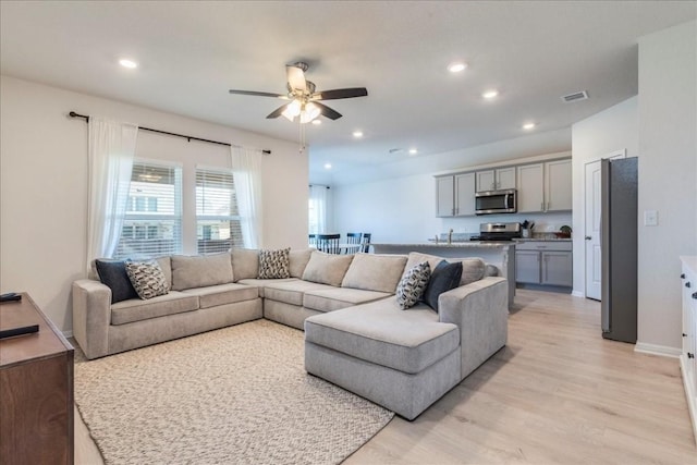living room featuring a ceiling fan, light wood-style floors, recessed lighting, and baseboards