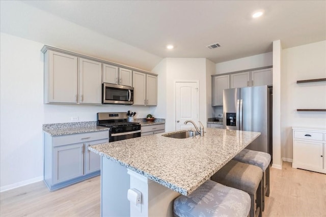 kitchen with appliances with stainless steel finishes, a sink, gray cabinets, light wood-type flooring, and recessed lighting