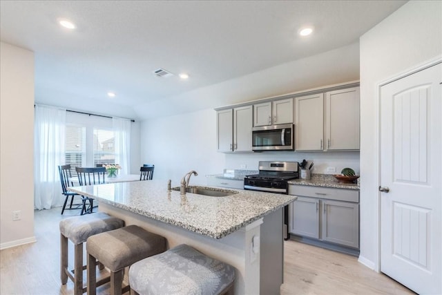 kitchen with appliances with stainless steel finishes, gray cabinetry, a sink, light wood-style flooring, and recessed lighting