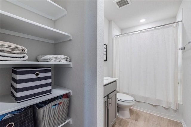 full bathroom with wood finished floors, toilet, vanity, and shower / tub combo