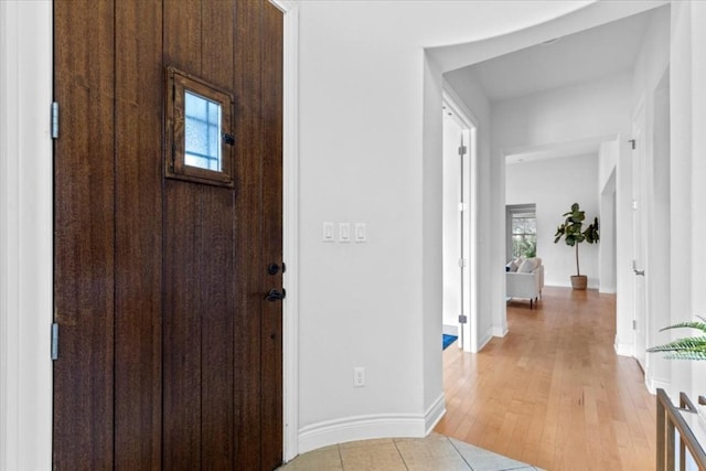 entrance foyer with light wood finished floors, a wealth of natural light, and baseboards