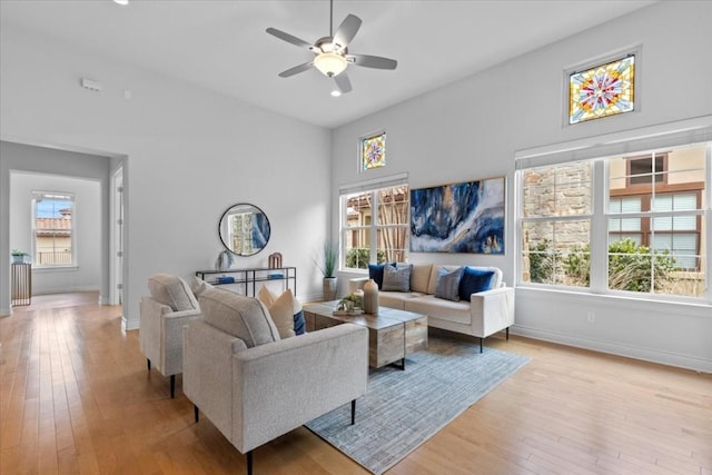 living room featuring baseboards, ceiling fan, and light wood finished floors