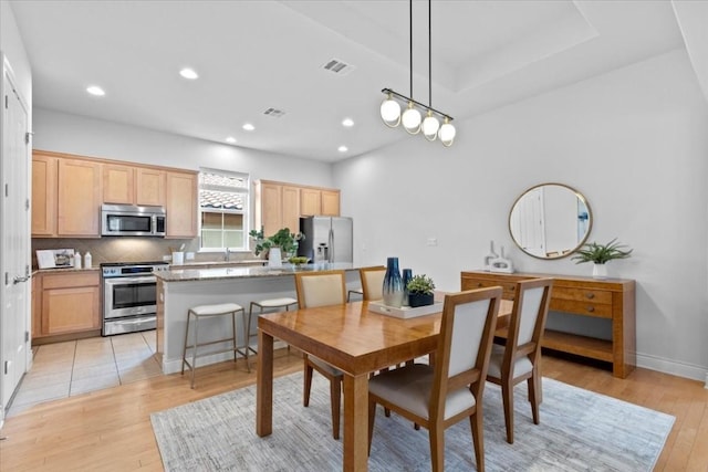 dining room featuring baseboards, light wood-type flooring, visible vents, and recessed lighting