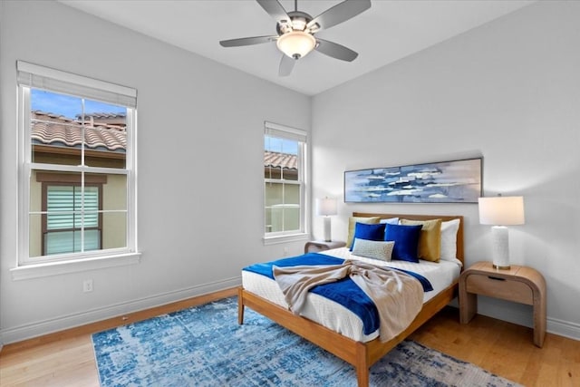 bedroom with a ceiling fan, light wood-style flooring, and baseboards