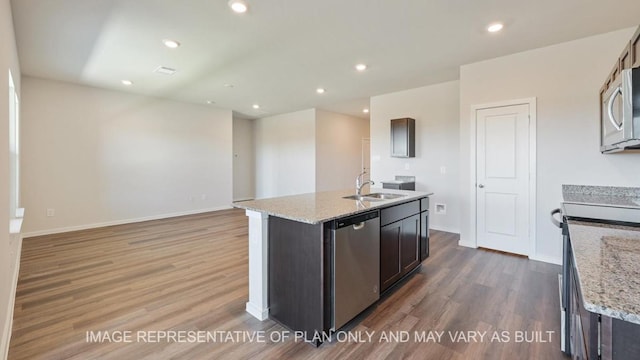 kitchen with appliances with stainless steel finishes, a sink, dark brown cabinets, and an island with sink