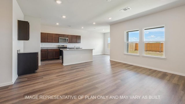 kitchen featuring stainless steel appliances, light countertops, visible vents, a kitchen island with sink, and wood finished floors