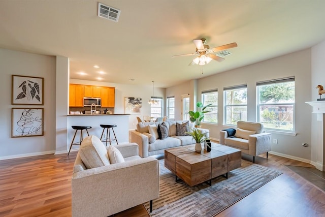 living room with light wood finished floors, visible vents, and baseboards