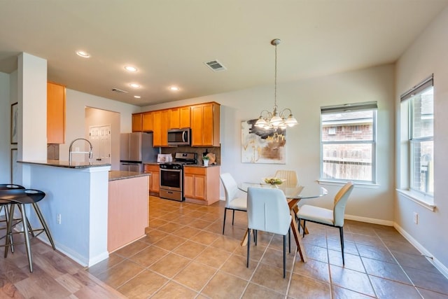 kitchen with visible vents, dark countertops, appliances with stainless steel finishes, a peninsula, and an inviting chandelier