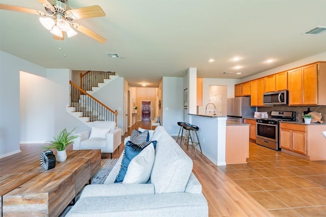 living room featuring light wood finished floors, stairway, visible vents, and recessed lighting